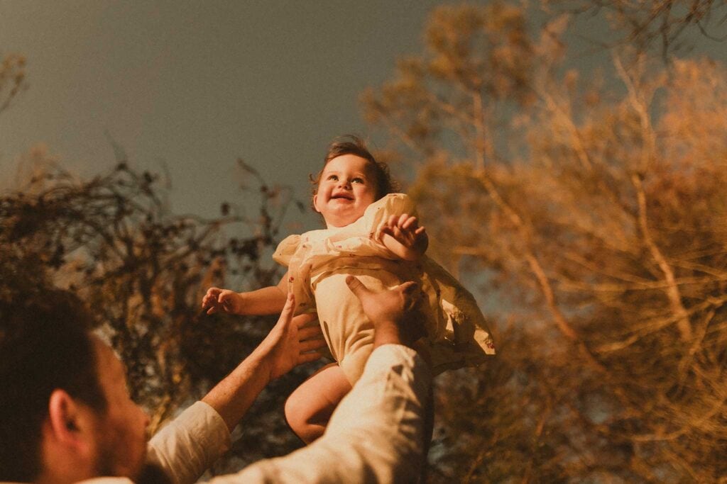 baby girl being thrown in the air during her first birthday photo shoot in Sydney